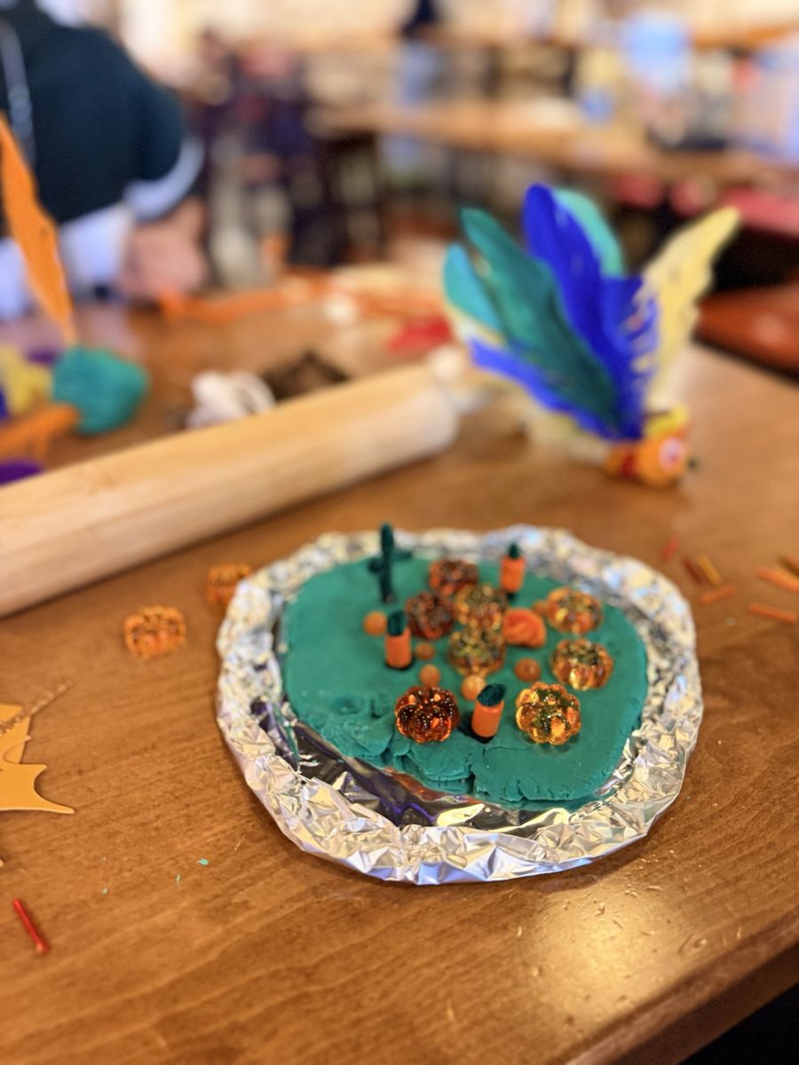 A playdough pumpkin patch with little acrylic pumpkins on green playdough
